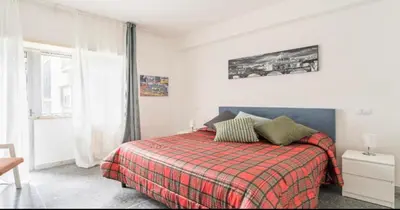 a bedroom with a bed with a plaid blanket and a window at Massi Vatican House in Rome