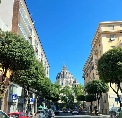 a city street with a dome in the background at Massi Vatican House in Rome