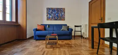 a blue couch in a living room with a table at Nox Romana Apartments - Vatican - Threeroom Apt with 2 Bathroom in Rome