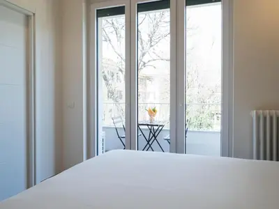 a bedroom with a white bed and a large window at Savoia Rooms Roma in Rome