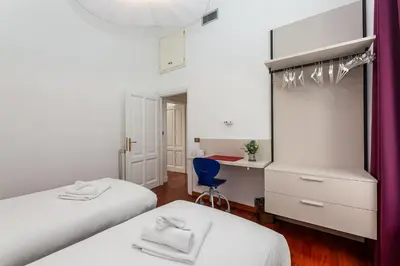 a bedroom with two beds and a desk and a blue chair at Aletheia Èlite - Elegant 2 BR in Rome