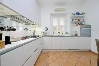 a kitchen with white cabinets and a tile floor at suity I cozy anglona apartment in Rome