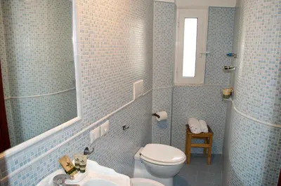 a blue tiled bathroom with a toilet and a sink at AmareRomaRooms in Rome