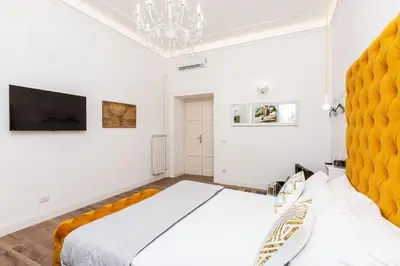 a white bedroom with a large bed and a chandelier at Portico d'Ottavia LUX in Rome