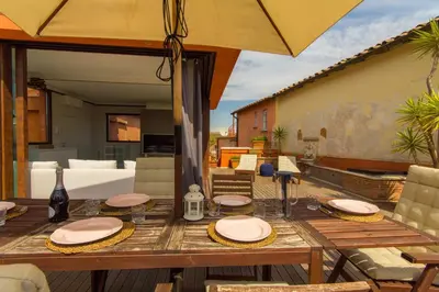 a wooden table with chairs and an umbrella on a patio at Pelliccia 11 Trastevere Penthouse in Rome