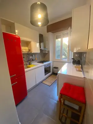 a kitchen with white cabinets and a red refrigerator at Appio11 Apartment in Rome