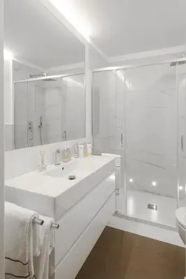 a white bathroom with a sink and a shower at Carthusia Suites Roma in Rome