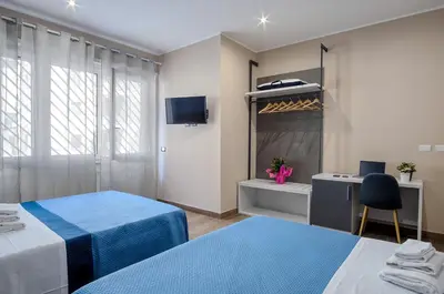 a room with two beds and a desk and a tv at Venturi Comfort in Rome