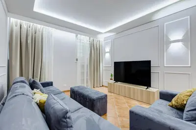 a living room with a blue couch and a flat screen tv at Spanish Steps Suite - Zucchelli in Rome