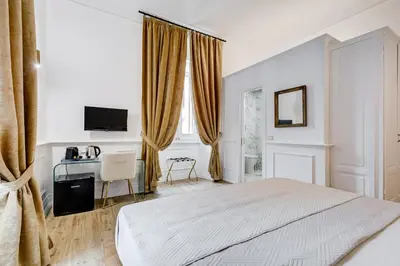 a white bedroom with a bed and a desk at Monti Suites Cavour in Rome