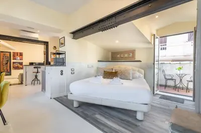 a bedroom with a large white bed and a kitchen at the B rooftop apartment in Rome
