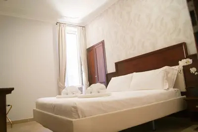 a bedroom with a bed with white sheets and a window at Glam Luxury Rome in Rome
